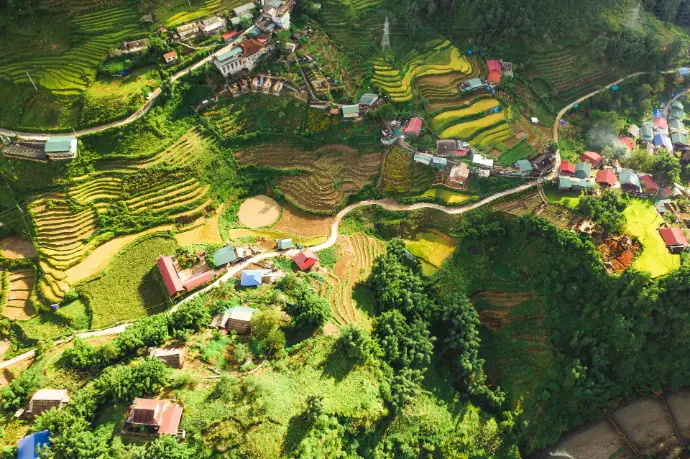 Aerial view of terraced rice fields and small houses in a mountain valley