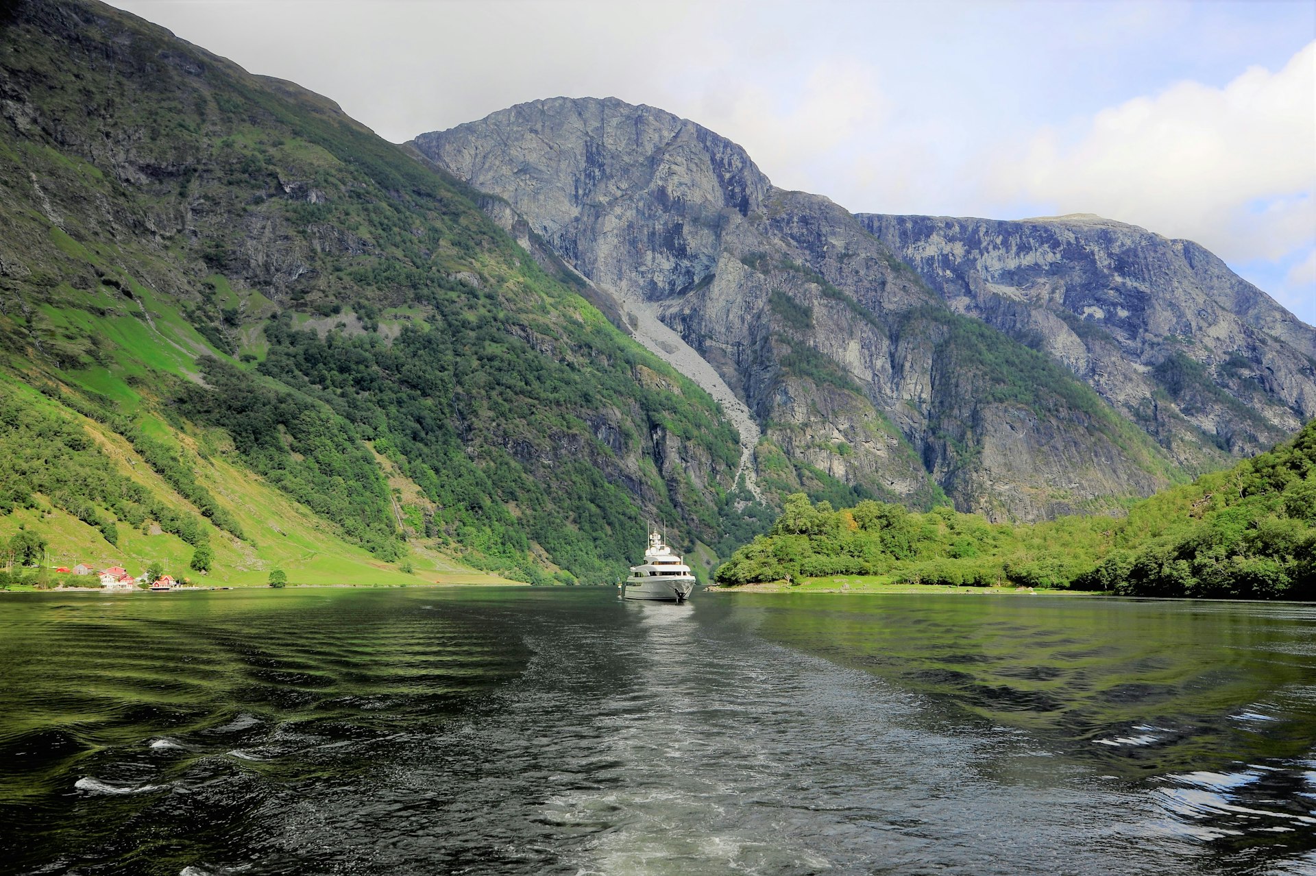 white boat on river near green mountain during daytime
